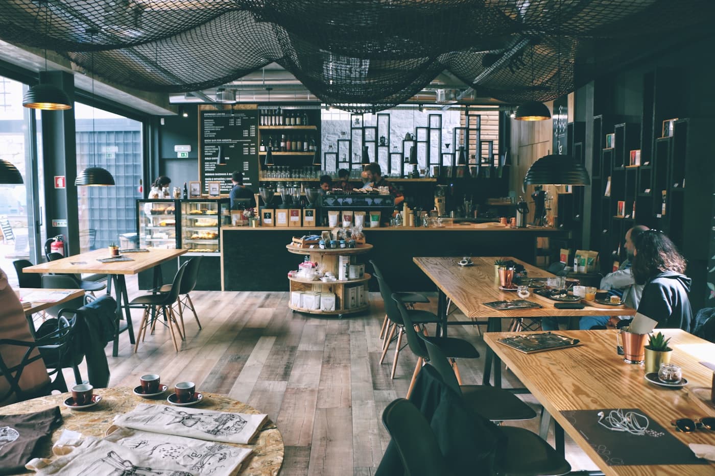 Guests working at communal tables in a sunlit coffee shop